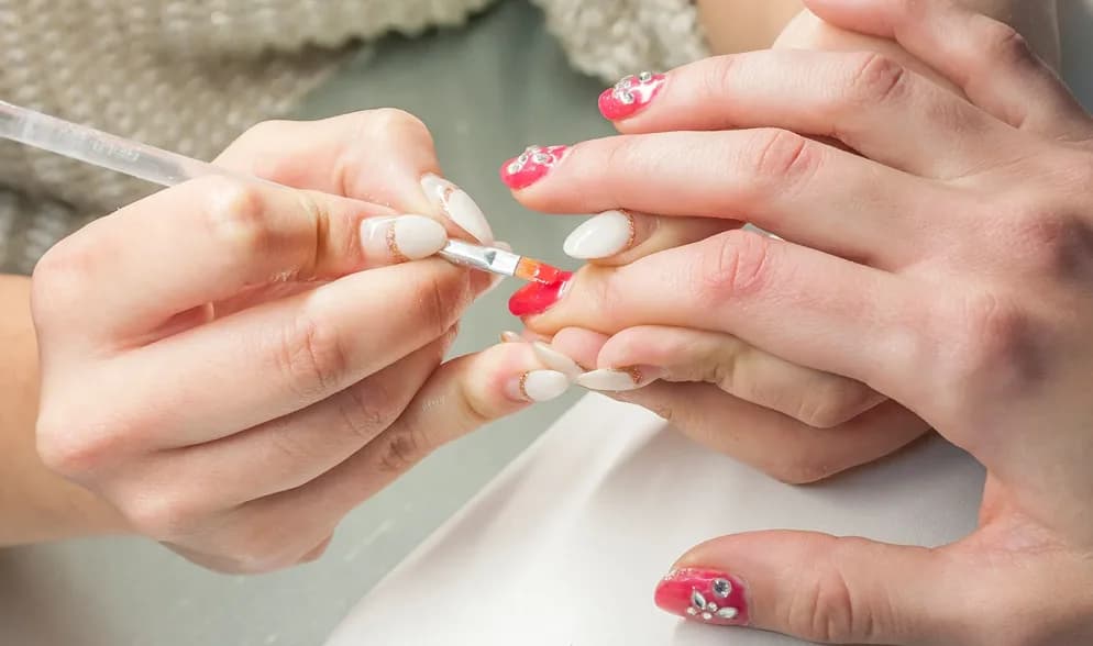 Tilburg'daki Charisma Clinic'te tırnaklara nail art tasarımı uygulayan tırnak stilisti